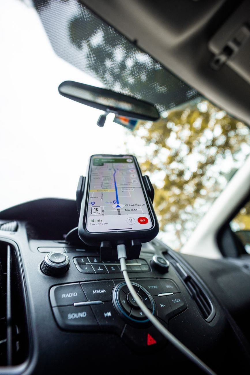 Smartphone mounted on car dashboard running a navigation app.